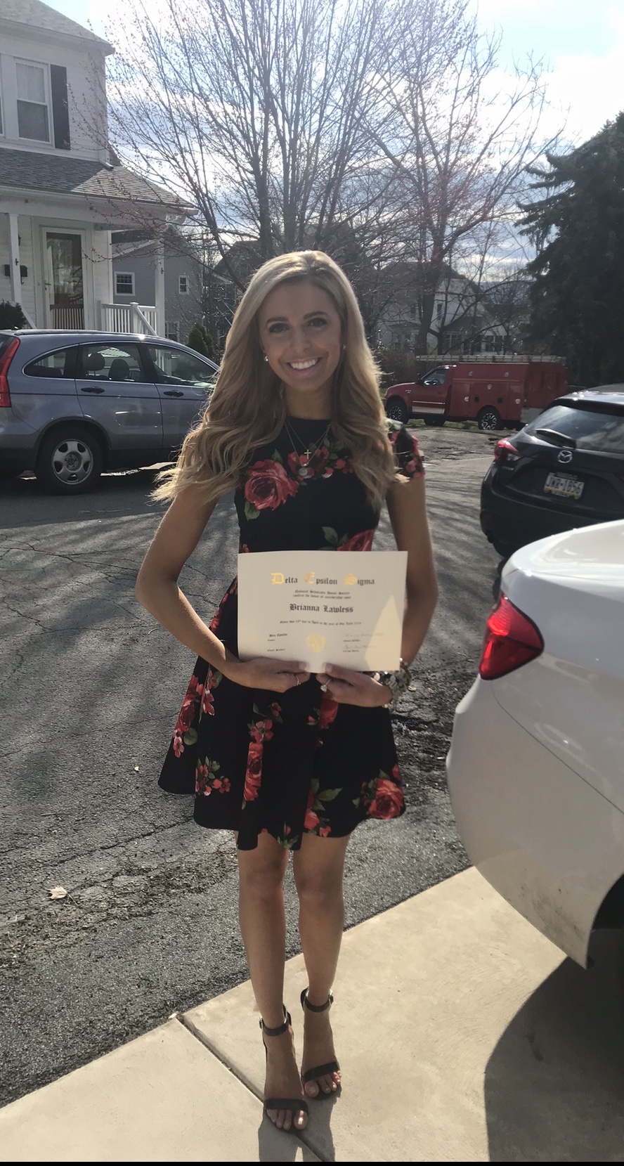 A young woman in a sundress holding a certificate.